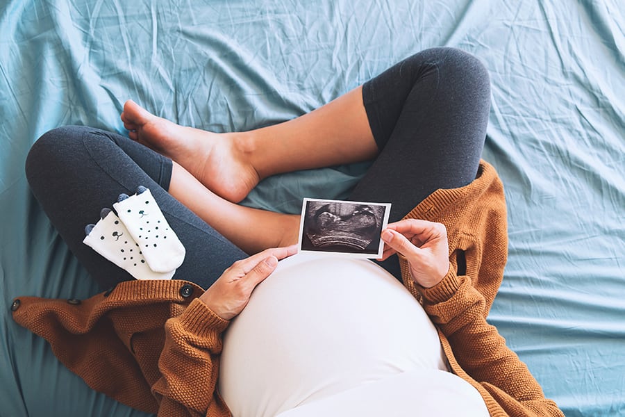 A pregnant woman holding a thermal ultrasound printout