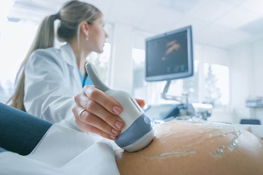 A doctor conducting an ultrasound on a pregnant belly