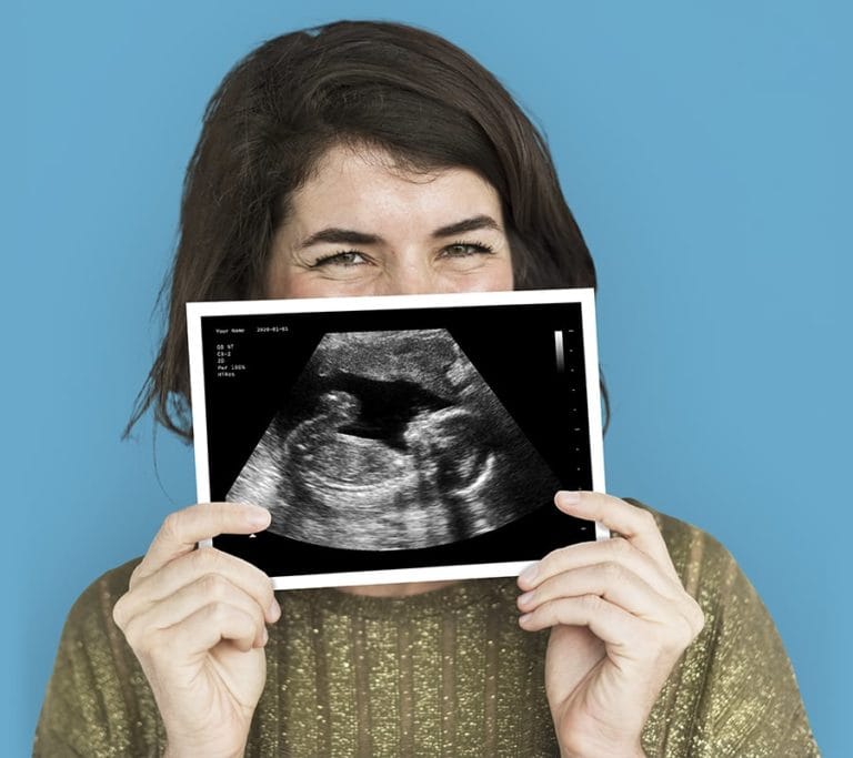 A happy woman holding one of Baby Maybes fake ultrasounds