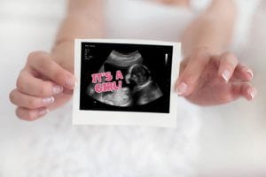 Isolated hands holding a gender reveal fake ultrasound
