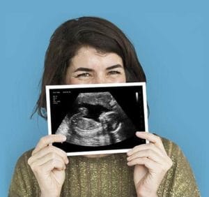 A happy woman holding one of Baby Maybes fake ultrasounds