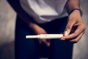 A woman holds a positive pregnancy test