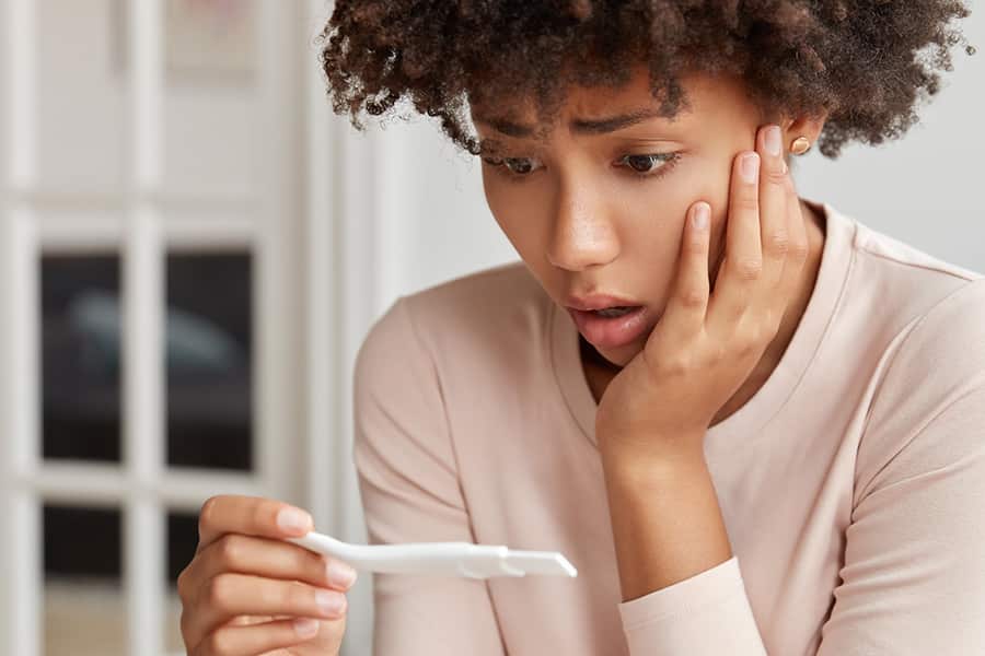 A woman looks shocked while looking at pregnancy test