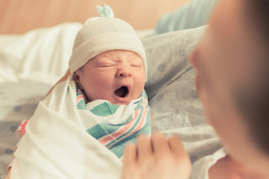 Mom looking at newborn yawning