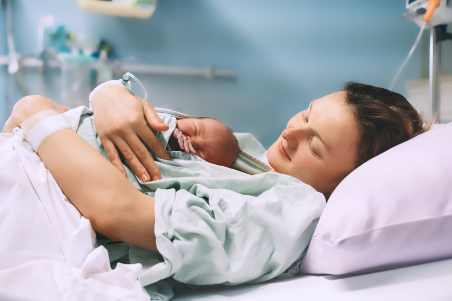 A mother holds her newborn child in the hospital bed