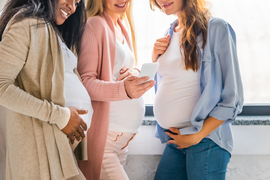 Three pregnant women looking at phone