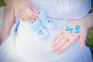 Pregnant woman holding blue socks