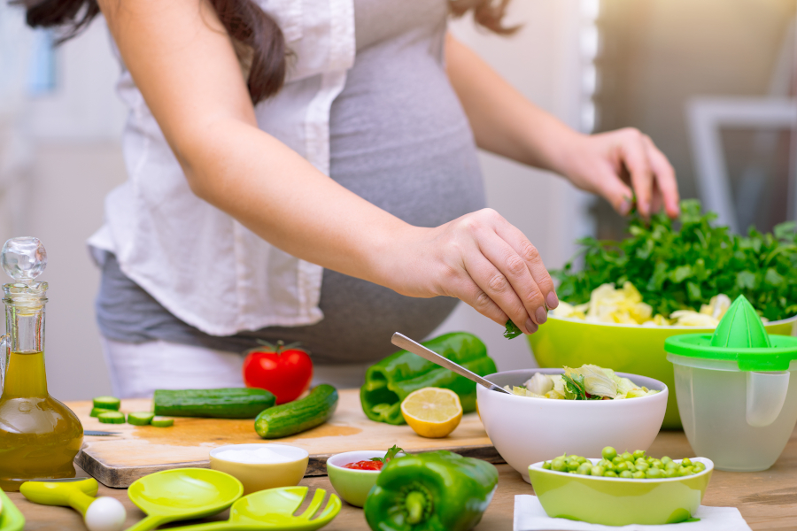 A pregnant woman making a salad