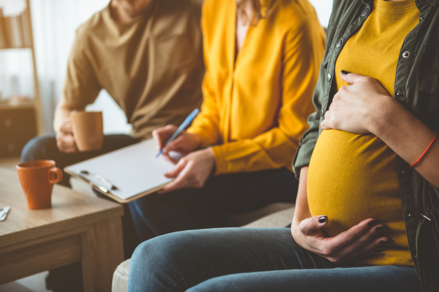 A couple signing a form with pregnant woman