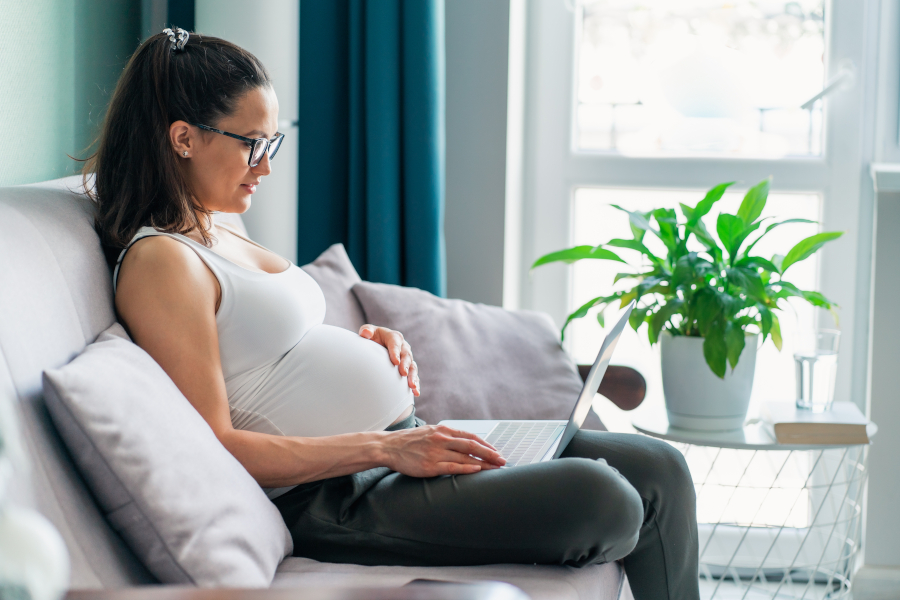 A pregnant woman works on a laptop