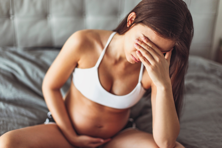 Pregnant woman looking tired in bed