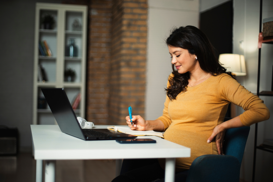 A pregnant woman working on a laptop