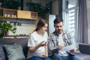 A couple looks at bills on a couch