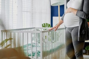 A pregnant woman looks at a crib at home