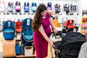 A pregnant woman is inspecting a stroller