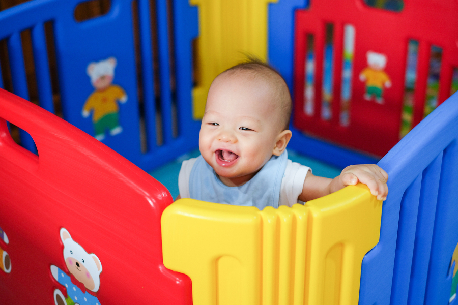 A baby standing in a playpen