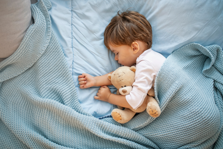 A baby sleeping with a stuffed bear